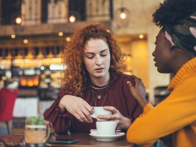 two women talking over coffee about serious topic